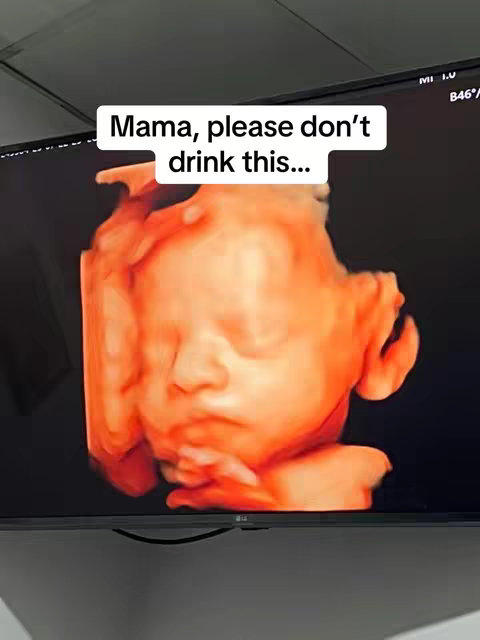 A close-up shot of an ultrasound image displayed on a black screen. The image shows a developing fetus, rendered in shades of orange and red, with the profile of the baby's face clearly visible, highlighted by the soft lighting. Above the image is a white text overlay saying, 'Mama, please don't drink this...'
