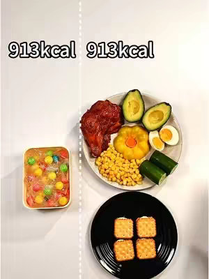 The image showcases a visual comparison of two food compositions. On the left, a transparent container filled with colorful candies and jell-o is positioned. On the right, a divided plate displays a variety of foods: a piece of roasted chicken, avocado halves, corn kernels, halved boiled eggs, and sliced cucumbers, alongside a black plate with four crackers. A vertical dotted line separates the two food setups, with the numbers "913kcal" displayed on either side, indicating their calorie count. The background is a clean white surface.