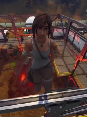 The image shows a female character from a video game standing on a metal structure. She is wearing a tank top, shorts, and has a determined expression. The background is a blend of industrial and natural elements, with some red fiery elements, and a blurred backdrop.