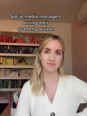 A woman with blonde hair and a white cardigan stands in front of a bookshelf filled with books. Text overlay at the top indicates "Social media managers during their quarterly review."