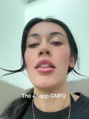 A close-up shot features a young woman with dark hair and a fair complexion. She has full lips with lipstick, and prominent eyebrows. Her eyes are visible through the top of the frame as she lightly parts her lips as if speaking. The background is an indistinct, light-colored wall. Overlay text appears below her face in a simple sans-serif font.
