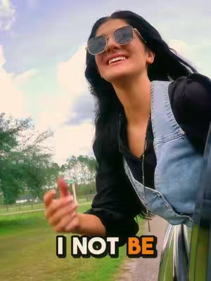 A woman in sunglasses smiles and leans out of a car window with countryside in the background. Overlayed are block letters in a bold font.