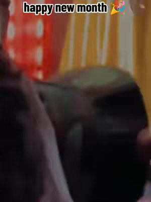 The image is slightly out of focus. In the background, a blurred red shape is visible, possibly a decoration or a fabric. The foreground is partially obscured and dark, suggesting a person or object is present but unclear. The text "happy new month" is overlaid at the top, accompanied by a party horn emoji.