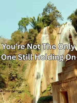 The cover image shows a waterfall cascading down rocks with lush green vegetation. Text overlay at the top reads, 'You're Not The Only One Still Holding On.' In the foreground, a building with a steeple is visible to the right. The overall composition is symmetrical, with natural elements dominating.