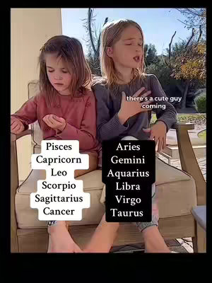 Two young girls are seated outdoors. One is on the left, looking downward with focus. The other, on the right, is mid-sentence, looking and pointing off-screen. Text overlays label the image with lists of zodiac signs, and speech bubbles state "there's a cute guy coming".