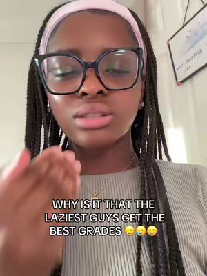 A close-up shot of a young woman with dark hair and glasses, wearing a headband and a casual top, looking slightly exasperated. Text overlaid on the image reads, "WHY IS IT THAT THE LAZIEST GUYS GET THE BEST GRADES 😭😭😭".