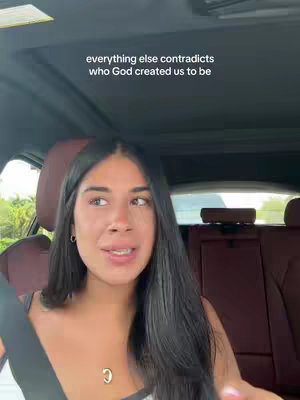 A selfie filmed from inside a car. A young woman with long, dark hair is in the foreground, looking toward the camera. The background is blurred, showing the inside of the car, with a red seat and the exterior through the windows. Text is overlaid at the top of the image.