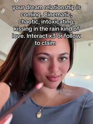 A selfie-style video cover featuring a woman with dark hair, gently smiling at the camera. She's holding a lip liner pencil. The cover also includes text overlays that talk about a dream relationship.