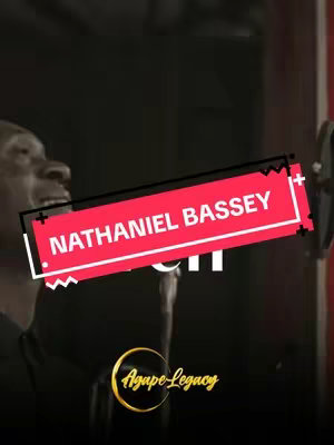 The cover image is a vertical shot highlighting a man, presumably the artist, singing into a microphone in a studio setting. The background is dark, focusing attention on the artist. A red and white text box overlay with the title 'NATHANIEL BASSEY' is prominently placed above the artist. The logo 'Agape Legacy' is located at the bottom of the image, a golden circle with a logo. The image has a warm, slightly desaturated color palette.