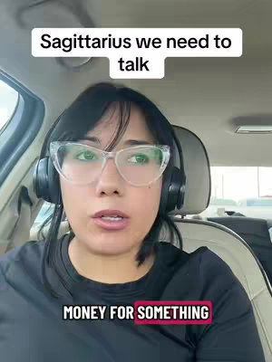 A woman is filmed from the chest up inside a car, with the camera angled slightly downward. She is wearing glasses and headphones and has text overlays. The lighting is natural, suggesting daylight.