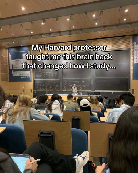 An image taken from the perspective of someone in a lecture hall. The hall appears well-lit, with rows of students facing a lecture desk. The image has text overlay with white font, which reads: 'My Harvard professor taught me this brain hack that changed how I study...'