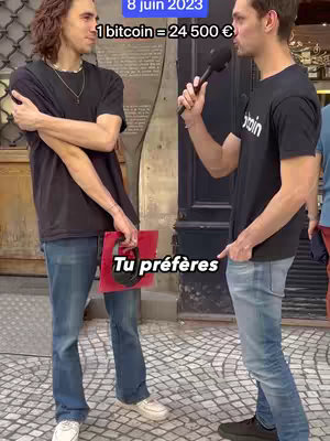 Two young men stand on a city street, one facing the camera holding a red object, and the other facing him holding a microphone. Text overlays the image indicating a date and a bitcoin price.