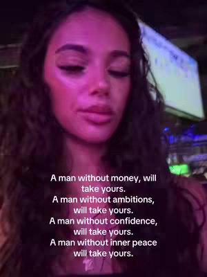A young woman with long dark wavy hair is centered in the frame, lit with a combination of fluorescent and ambient lighting. The background is dimly lit, setting off the subject's face. Text overlayed on the image reads 'A man without money, will take yours. A man without ambitions, will take yours. A man without confidence, will take yours. A man without inner peace will take yours.'