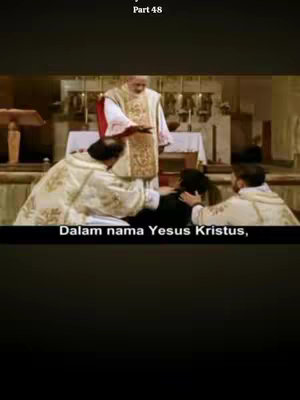 The cover image shows a scene from a film depicting a religious ceremony. In the center, a priest in elaborate vestments is conducting a blessing, with his hands raised. Two other priests are assisting, one kneeling with hands on the head of a person, and the other supporting their back. The setting appears to be a church interior featuring an altar and religious artifacts. The image has a muted color palette, and text is added at the top and bottom of the frame.