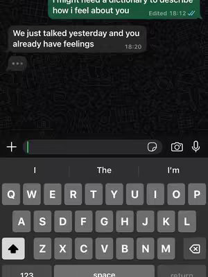 A screenshot of a mobile phone displaying a text message conversation. The background is dark gray. There are two message bubbles. The top one is green and reads, "I might need a dictionary to describe how I feel about you." Edited 18:12. The second is white and reads, "We just talked yesterday and you already have feelings." 18:20.  At the bottom of the screen is a keyboard with keys for letters, numbers, and punctuation.
