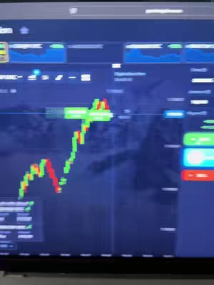 A screenshot of a computer screen displaying a trading platform with a price chart. The chart shows a fluctuating green and red line against a dark background. There are several other numerical data and trading controls.