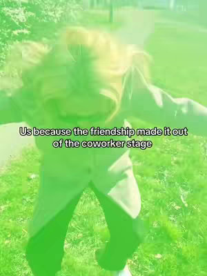 An overhead shot of a person in a green outfit jumping in front of grassy background. A text overlay reads 'Us because the friendship made it out of the coworker stage'.