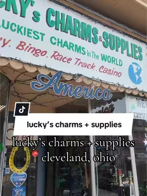 The cover image shows the exterior of a shop, labeled "Lucky's Charms & Supplies". The shop has awnings, with signs indicating various services such as lucky charms, bingo, and a casino. The words  "America" are displayed across.