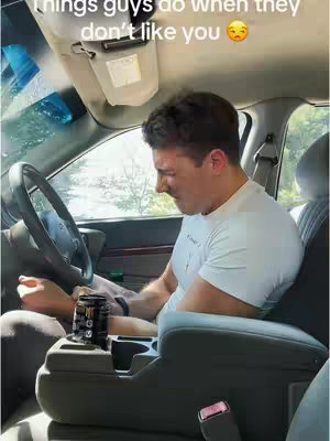 An interior shot shows a man in a car, seemingly deep in thought or sadness. He's positioned in the driver's seat, with the steering wheel visible. His face is partly obscured but conveys the emotion of the video. The car's interior, including the console with a drink, is in focus.