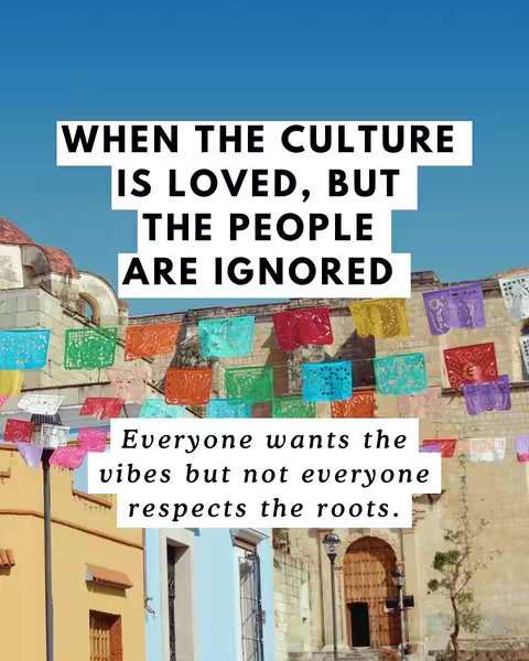 The cover image features a clear blue sky with colorful rectangular paper flags strung across the scene. Buildings with architectural details, including arched doorways and windows, form a backdrop. Overlaid on the scene are two white rectangular text boxes. The upper text box states, 'WHEN THE CULTURE IS LOVED, BUT THE PEOPLE ARE IGNORED.' The lower text box says, 'Everyone wants the vibes but not everyone respects the roots.'