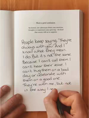 An open book is displayed on a wooden surface, with handwriting filling a page. The text, written in a casual script, expresses feelings about loss and grief. A hand with a pen is visible, and colors are muted.