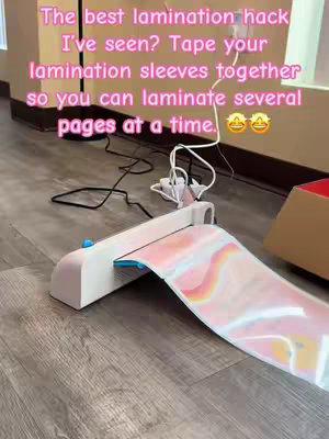The image is a medium shot of a laminator on a wooden floor, with a text overlay.  The floor is a light brown. On the left, the device is a cream-colored laminator. The text includes highlighting on how to laminate pages. Light from a window filters in the background.