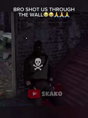 The image shows a scene from a video game. A person, possibly the character, is kneeling in a dark, brick-walled area. They wear a black outfit with a skull and crossbones on the chest. Above the character, text overlays read, “BRO SHOT US THROUGH THE WALL” with some emojis. In the bottom right, a YouTube logo, along with a profile named SKAKO.