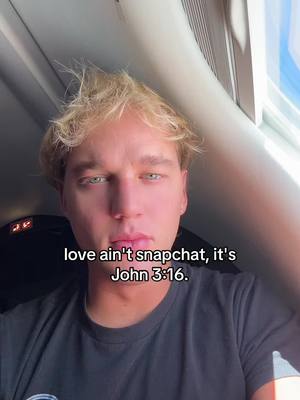 A selfie-style video cover image featuring a young man with light-colored hair. The man is looking directly at the camera with a serious expression. The text overlay at the bottom shows 'love ain't snapchat, it's John 3:16.' The background is a blurred interior scene.