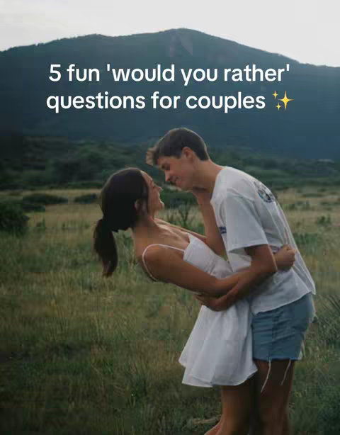 A couple embraces in a field, with a mountain in the background. The woman is wearing a white dress and the man is wearing a white t-shirt and blue shorts. Text overlay indicates the video is about questions for couples .