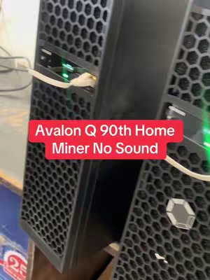 The image features two black rectangular devices, possibly computer servers or mining rigs, arranged side by side. They have a mesh design on their front panels and visible internal components. A red rectangle with white text is superimposed on the image, labeling "Avalon Q 90th Home Miner No Sound."
