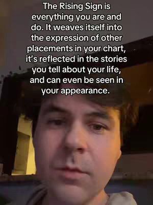 A medium shot shows a man's face, centered in the frame. Text is overlaid at the top, stating that the rising sign is everything you are and do, and influences your chart placements, the stories you tell, and even your appearance. The man has short brown hair and is looking directly at the camera with a slight furrow in his brow.