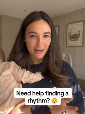 A woman holding a baby, looking at the camera and speaking. Text overlaid on the image says, "Need help finding a rhythm?" with a surprised baby emoji.