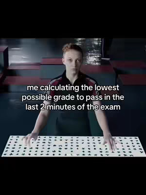 The cover image is a still from a movie, likely "The Hunger Games", featuring a young woman with auburn hair looking intently at a geometric display, possibly a control panel or interface. The background is dark, with vertical red and gray accents. The text overlay states, "me calculating the lowest possible grade to pass in the last 2 minutes of the exam".