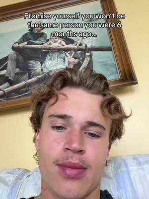 A young man's face is centered in the frame, with a framed painting visible in the background. The man has short, curly brown hair and a slightly open-mouthed expression. Above him, the painting shows a scene with figures in a boat and text that says, 'Promise yourself you won't be the same person you were 6 months ago...'
