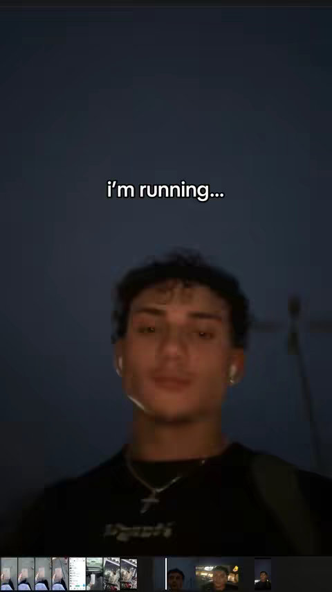 The image is a selfie of a young man with curly hair against a dark, possibly night sky. The text overlay says "i'm running...". The man wears a dark t-shirt and a necklace. The lower portion of the image shows thumbnails of other images, indicating a video editing interface.