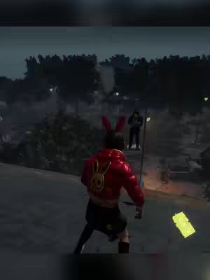 A nighttime scene from a video game. The main subject, seen from the back, wears a red jacket with a bunny skull emblem. They are in a dimly lit, perhaps urban environment with trees and streetlights. A second figure stands in the distance. A yellow in-game item floats nearby.