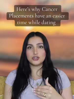A woman with long black hair and a light purple top is centered in frame, with a blurred sunset-like background. A text overlay in a brown rectangle is above her head.