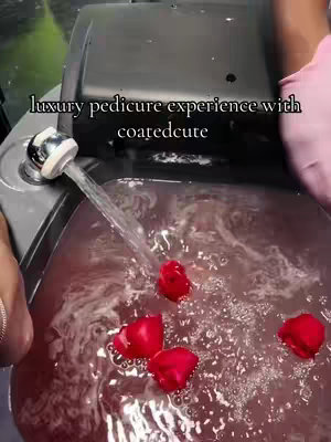 Overhead shot of a pedicure setup. The image predominantly features a foot spa with water and red rose petals. A spout is pouring water into it. The hands of someone in pink gloves are on the right, and a person's hand with jewelry is visible on the left. The hook text is at the top.