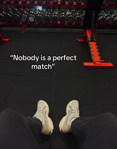 The cover image shows a person's perspective looking down, with their legs and feet wearing white sneakers visible in the foreground. The floor is black, and in the background, there are gym equipment like weights and benches. Text in the image says, "Nobody is a perfect match."