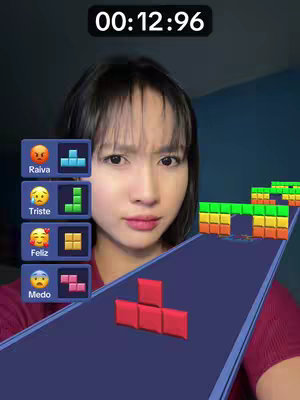 The cover image features a young woman with dark hair and a neutral expression, framed in a face close-up. She appears to be looking slightly off-camera. The background is a blurred gradient of dark blue and what appears to be part of a game, indicated by the game interface elements, with colored blocks. The overall color scheme is dark with colorful accents from the game interface.