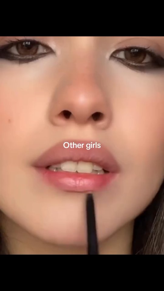 A close-up shot focusing on a person's face, specifically their mouth and eyes. The person is wearing makeup, with prominent eyeliner and a soft lip color. The text "Other girls" is superimposed on the image.