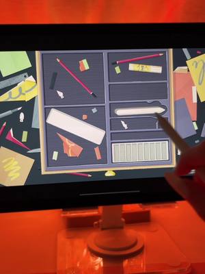 The cover image shows a computer screen displaying a game interface, displaying a drawer filled with various neat objects. A hand with a stylus is in the process of interacting with the items on the screen. The scene has a warm, orange ambient lighting.