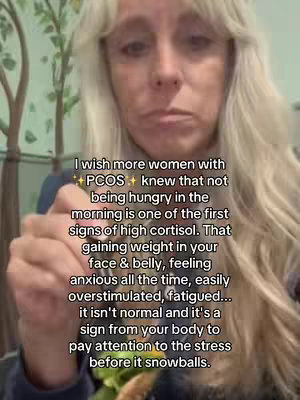 A woman with long, graying blonde hair is speaking in the frame. She is holding something near her mouth, possibly food. Text is overlaid on the image, explaining the connection between PCOS and cortisol levels.
