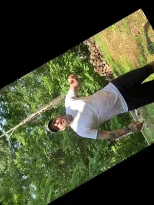The cover image features a man dressed in a white t-shirt, black shorts, and a black cap, set against a backdrop of lush greenery including trees and grass. The composition is skewed at an angle.