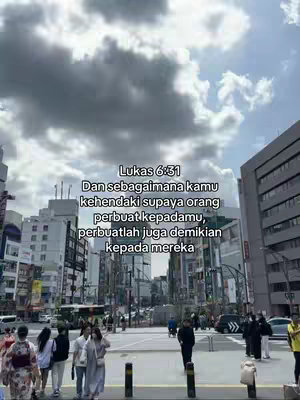 The cover image shows a street scene in a city with tall buildings and people walking. The sky is cloudy. Text in Indonesian is overlaid on the image, with a Bible verse from Luke.