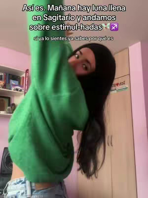 A woman with long black hair in a green sweater is partially visible, arms overhead, in front of a background of a cluttered room. Text overlays the image.