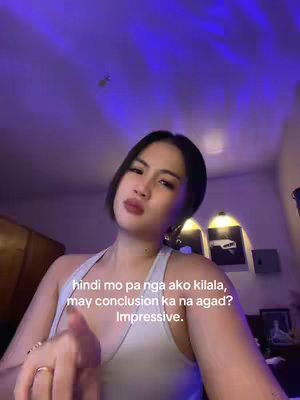 A young woman with dark hair, wearing a white tank top, and red lipstick is looking at the camera. The background has dim, purple lighting and suggests a home setting. The text overlays read "hindi mo pa nga ako kilala, may conclusion ka na agad? Impressive."
