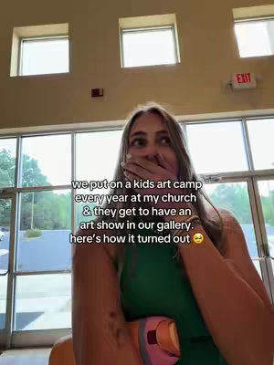 The cover image shows a woman holding her hands up to her mouth in surprise, likely reacting to something. She appears to be indoors, standing in front of large windows that let in natural light. Text overlays are placed on the image, describing the context for the video. The overall aesthetic is natural and candid.