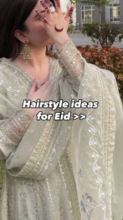 The cover image features a woman wearing a light green embroidered outfit, with her right hand covering her face near her eye, showing a crescent moon henna tattoo. The background is blurred, which includes greenery and buildings.