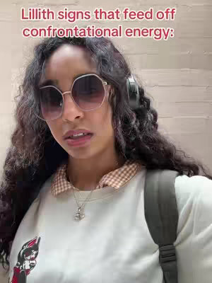 A young woman with long, dark curly hair and large sunglasses gazes slightly off-camera, wearing a white sweatshirt and a patterned collared shirt underneath. Text overlay on the top indicates the video's topic.